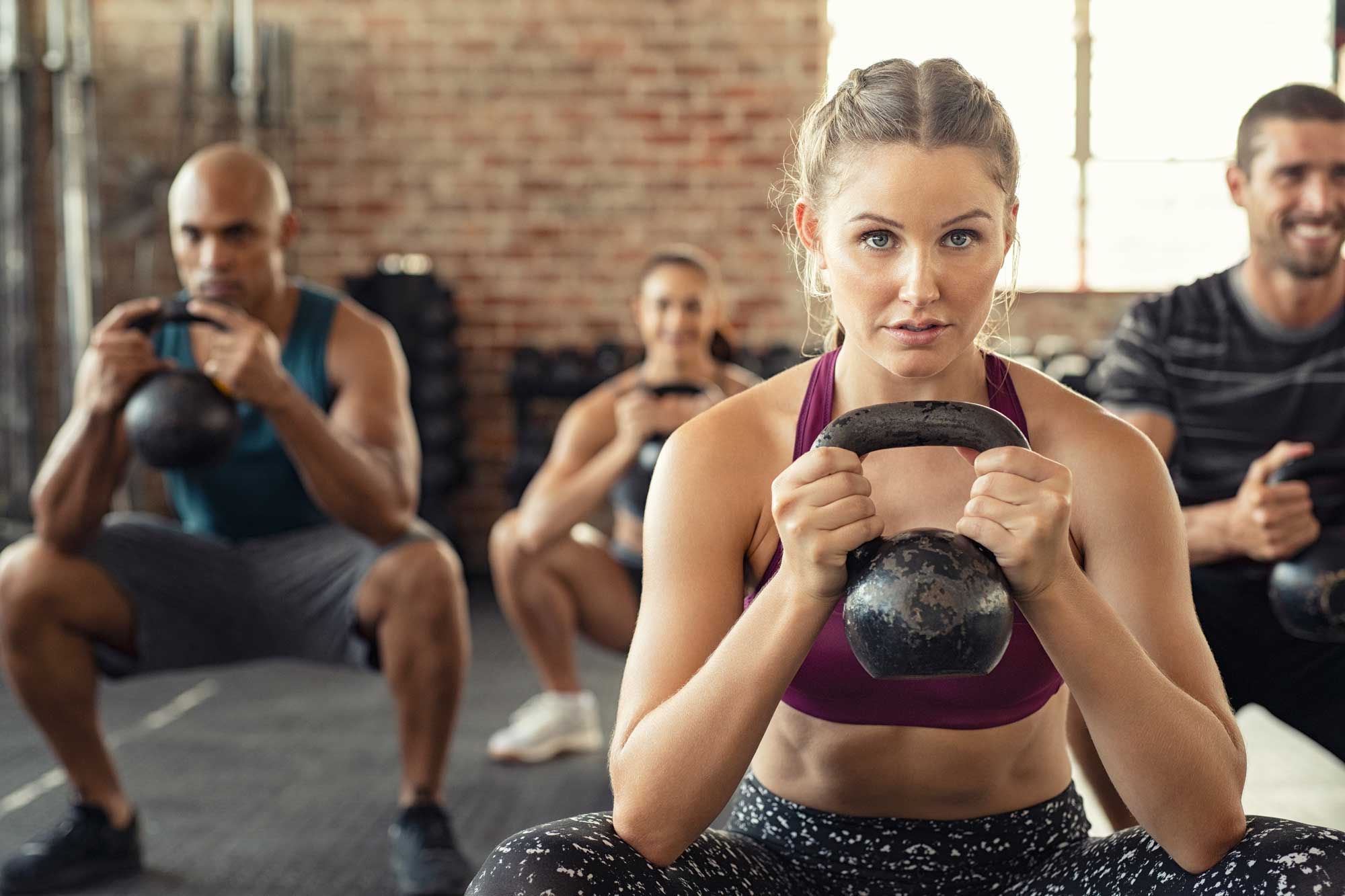 Personer har ett grupppass med en kettleball.